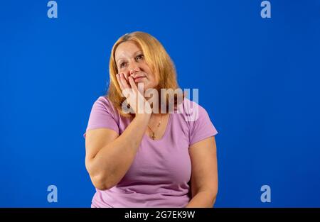 Media età bella donna che indossa camicia casual viola su isolato sfondo blu annoiato stanco coprire la bocca con la mano. Irrequieta e. Foto Stock