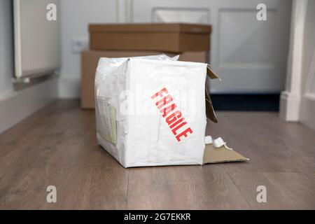 Sbattete la scatola di consegna danneggiata con un adesivo fragile, una confezione di cartone di consegna rotta a casa Foto Stock