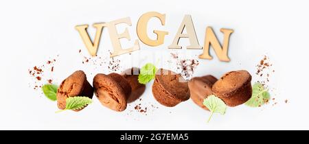 Muffin al cioccolato con foglie di menta su sfondo grigio chiaro, scritte VEGANE realizzate con striscioni di lettere in legno Foto Stock