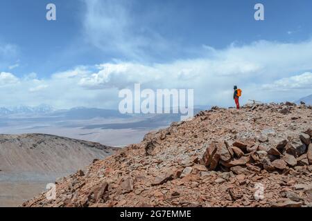 Un uomo sulla cima del vulcano Siete Hermanos si sente felice di fronte a un paesaggio mozzafiato nel deserto di Atacama vicino Copiapo Foto Stock