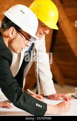 Piani e progetti di discussione di architetti e ingegneri edili o topografi. Entrambi indossano i cappelli duri e sono in piedi sul luogo di costruzione o Foto Stock