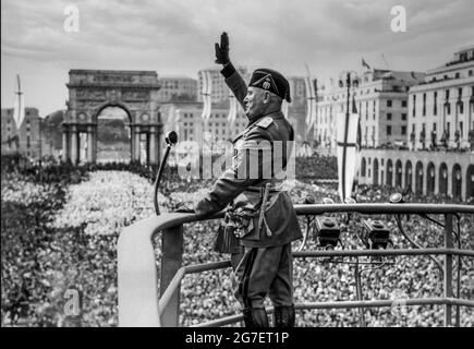 MUSSOLINI DISCORSO 1930s il DULCE ROMA ITALIA DISCORSO fascista italiano Benito Mussolini al culmine della sua popolarità, in uniforme militare con microfono facendo un discorso sul podio rialzato, facista salutando le estatiche folle italiane a Roma Italia nel 1930s. Foto Stock