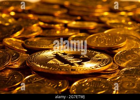 Criptovaluta d'oro Bitcoin sullo sfondo di molte altre monete d'oro in luce dura. Nuovo concetto del crescente valore di blockchain basato Foto Stock
