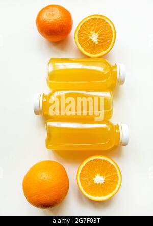 Bottiglie di succo d'arancia appena spremuto e arance su sfondo bianco. Il concetto di una dieta sana, disintossicazione o dieta Foto Stock