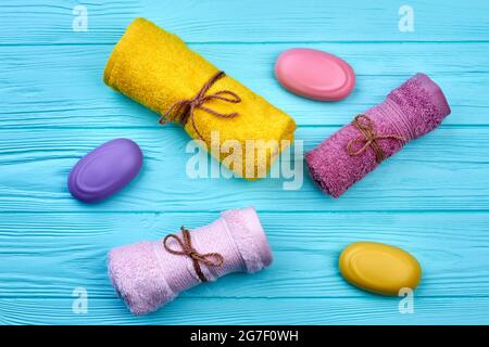 Asciugamani e sapone rotolati su scrivania di legno blu. Foto Stock