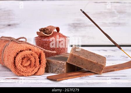 Asciugamano marrone arrotolato con saponette e sale per la terapia termale. Foto Stock