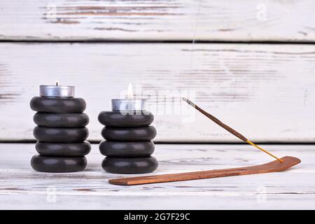 Pietre nere con candele e bastoni per trattamenti termali. Foto Stock