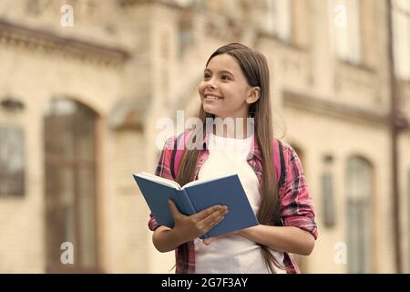 Immaginazione e creatività contemporaneamente. Libro di tenuta felice del bambino con lo sguardo pensivo. Istruzione scolastica. Fantasia e pensiero fantasioso. Conoscenza e. Foto Stock