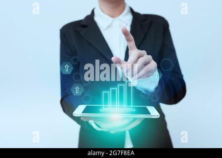 Donna in piedi uniforme che trasporta il telefono puntando sulle icone di display di interfaccia virtuale. Lady in Suit Holding Mobile Device indica l'innovazione Foto Stock