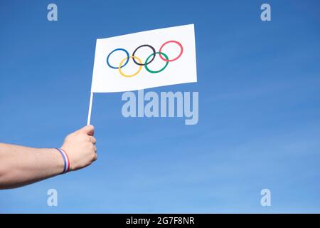 Mano che tiene una bandiera fatta a mano dei Giochi Olimpici all'aperto, contro un cielo limpido, con un bracciale rosso, bianco e blu, Croazia, Paesi Bassi e Paraguay na Foto Stock