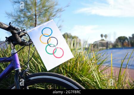 Bandiera olimpica fatta in casa di carta messa sulla parte anteriore di una bicicletta, all'aperto, in un ambiente sportivo, una giornata di sole. Immagine con spazio di copia. Foto Stock