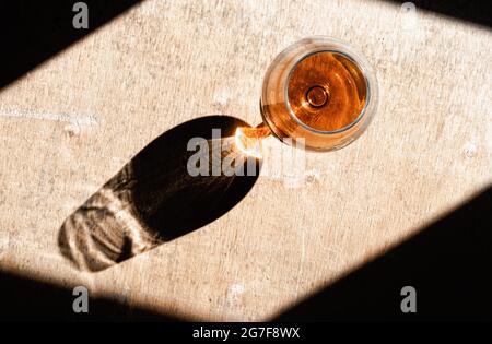Primo piano dell'ombra del bicchiere di champagne sotto la luce del sole. Vista dall'alto. Foto Stock