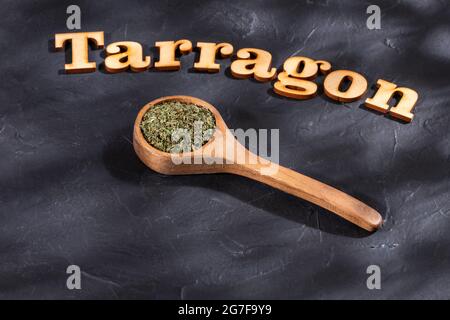 Foglie di dragoncello organico essiccato in cucchiaio di legno - Artemisia draconculus Foto Stock