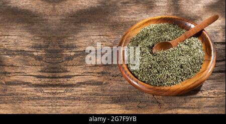 Artemisia draconculus - foglie di dragoncello organico essiccato in ciotola di legno Foto Stock