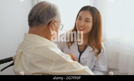 La donna infermiera medico indossa un cardiologo bianco uniforme che esamina il paziente anziano o anziano anziano durante la seduta su sedia a rotelle che ascolta il controllo battito cardiaco Foto Stock