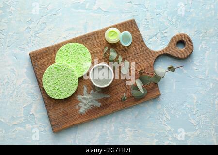 Composizione con spugne e prodotti cosmetici su sfondo colorato Foto Stock