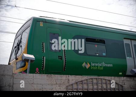 GREYSTONES, IRELAND - 07 giu 2021: Scatto a basso angolo di un treno espresso interurbano con il logo visibile della ferrovia irlandese in lingua irlandese e inglese. Foto Stock