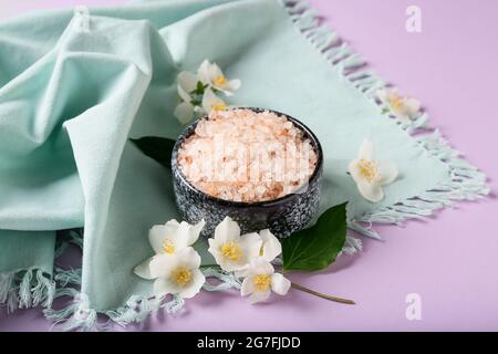 Composizione con ciotola di sale marino e fiori di gelsomino su sfondo colorato Foto Stock