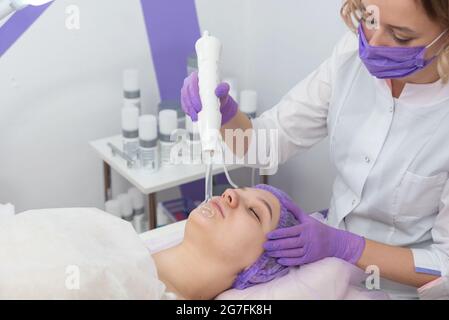 Salone di bellezza. Il cosmetologo effettua una procedura di peeling dell'acqua per il cliente. Vista laterale. Il concetto di cura professionale della pelle. Foto Stock