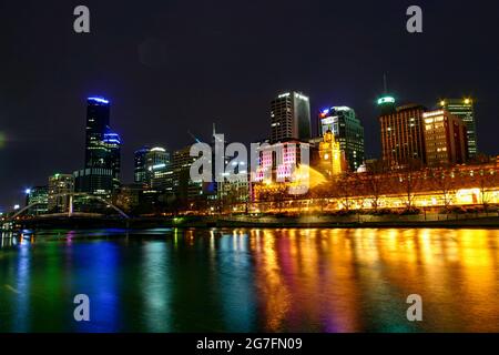 Colorato lungomare della città di Melbourne e Flinders Street Station edificio storico con luci che si riflettono al largo dell'acqua Foto Stock