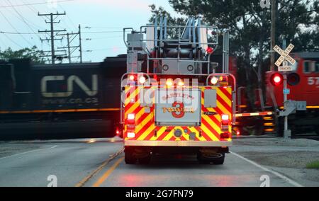 Bartlett, Illinois, Stati Uniti. 13 luglio 2021. 13 luglio 2021 - Bartlett, Illinois, Stati Uniti - UN camion del fuoco di Bartlett, Illinois nel percorso ad una chiamata è fermato ad un incrocio ferroviario da un treno ferroviario nazionale canadese. Credit: H. Rick Bamman/ZUMA Wire/Alamy Live News Foto Stock