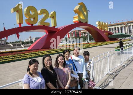 Pechino, Cina. 09 luglio 2021. Un gruppo di turisti scatta foto sotto l'emblema del Partito Comunista in Piazza Tiananmen a Pechino. Dopo l'incontro che celebrava il centesimo anniversario della fondazione del Partito Comunista Cinese il 1 luglio, Piazza Tiananmen è stata decorata con installazioni commemorative che sono diventate un'opportunità fotografica popolare per i turisti. Le strutture rimarranno in vigore fino al luglio 31. Credit: SOPA Images Limited/Alamy Live News Foto Stock