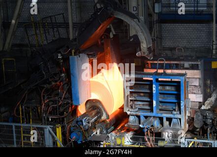 13 luglio 2021, Brandeburgo, Eisenhüttenstadt: Una lastra rossa-calda viene avvolta in una bobina nel laminatoio a caldo di ArcelorMittal. Le lastre utilizzate sono spesse 225 millimetri e lunghe fino a 12 metri. Dalle lastre vengono prodotte bobine a caldo con un peso massimo di 34 t. Foto: Soeren Stache/dpa-Zentralbild/dpa Foto Stock