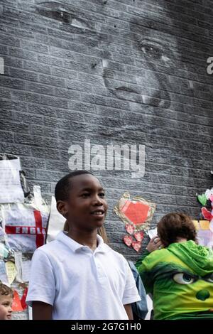 Marcus Rashford Street art, Withington dopo la riparazione di Akse P19. Ragazzo in piedi di fronte al murale. Withington, Manchester Regno Unito Foto Stock