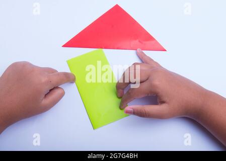 Mano umana che piega una carta colorata isolata su sfondo bianco Foto Stock