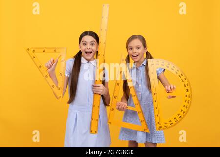 Torna a scuola è qui. Le ragazze felici tengono gli attrezzi geometrici. Ritorno a scuola. Lezione sulla geometria Foto Stock