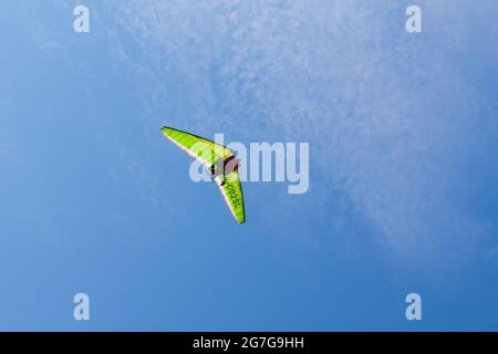 volo libero di un deltaplano verde nel cielo blu estivo Foto Stock