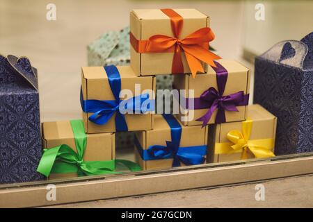 Le confezioni regalo, avvolte in carta e decorate con nastri colorati, sono in appoggio su inrow. Regali e sorprese. Vacanze e decorazioni. Stile di vita. Foto Stock