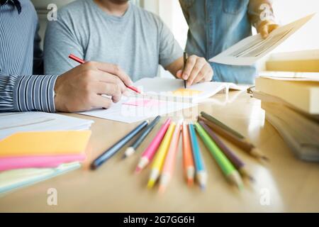 Educazione, insegnamento, apprendimento e concetto di persone. Gruppo di studenti delle scuole superiori o compagni di classe con aiuta gli amici a recuperare l'apprendimento del libro degli esercizi in classe Foto Stock