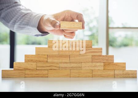 Piano e strategia nel business, rischio di fare business crescita concetto con blocchi di legno, mano di uomo ha impilato e un blocco di legno. Foto Stock