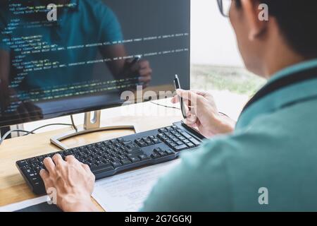 Giovane programmatore professionale che lavora allo sviluppo di programmazione e sito web lavorando in un ufficio di sviluppo di software aziendale, scrivere codici e dat tipizzazione Foto Stock