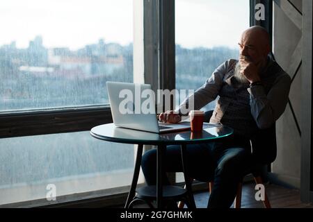 uomo d'affari pensieroso seduto ad un tavolo in un caffè. Foto Stock