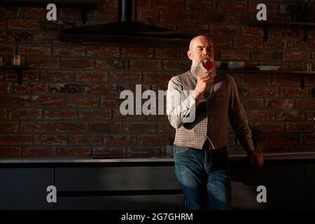 bell'uomo che guarda il vino rosso nel bicchiere . Foto Stock