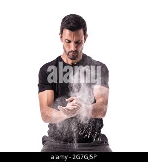 Atleta europeo che si prepara ad allenarsi, aggrappando le mani, con gesso, sollevando una nuvola. Su uno sfondo bianco isolato. Foto Stock