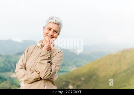 Adulto non shaven afroamericano maschio con mano in tasca surf internet sul cellulare contro la parete alla luce del sole Foto Stock