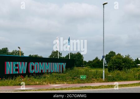 Le parole Nuova Comunità sono state dipinte su una recinzione nera accanto a un campo vuoto. Cambridge, Regno Unito. Foto Stock