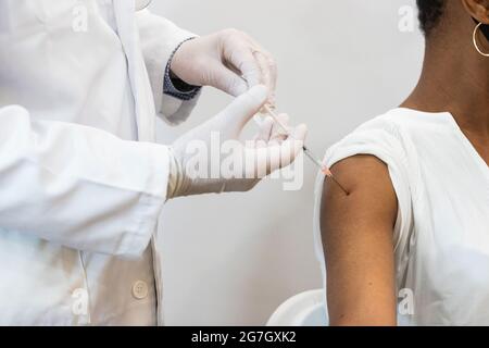Primo piano della medica di coltura che fa l'iniezione per la paziente femmina nera Foto Stock