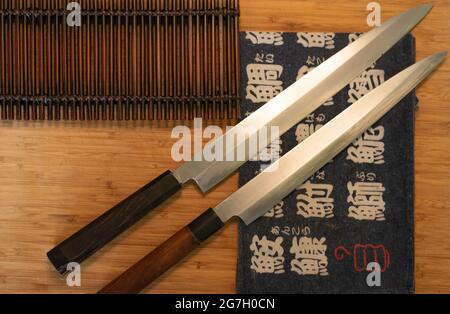 Vista dall'alto di coltelli affilati e tappetino per sushi collocato su un tavolo di legno nel ristorante asiatico Foto Stock