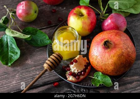 Immagine religiosa del concetto di Rosh hashanah (festa ebraica di Capodanno). Simboli tradizionali: Miele, mele e melograno su un tavolo rustico scuro. Foto Stock
