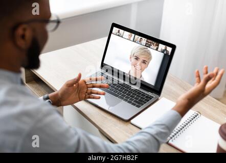 Chat video di gruppo online. Vista a spalla di un uomo d'affari nero che parla utilizzando una conferenza con webcam su pc con diversi colleghi, un dipendente maschile Foto Stock