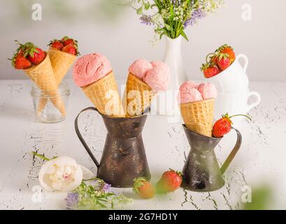 Gelato alla fragola con fragole fresche in cialde su sfondo bianco di legno Foto Stock