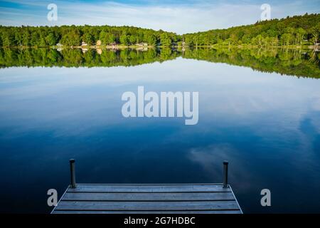 Lago splendidamente placido visto dal molo su un lago vicino a Copperstown, NY, USA. Foto Stock