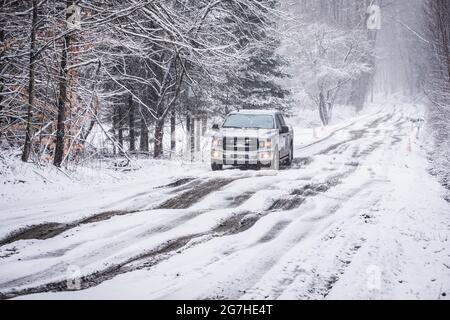 Camion negozia fangoso, strada sterrata nevosa durante la stagione di fango a Montpelier, Vermont, New England, USA. Foto Stock