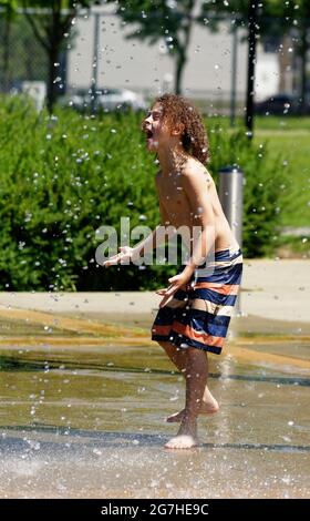 Un ragazzo (9 anni) che gioca in giochi d'acqua e fontane a Quebec City, Canada Foto Stock