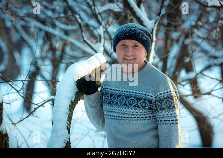 Ritratto di un uomo in una giornata innevata nella foresta. Il ragazzo in abbigliamento sportivo invernale. Foto Stock