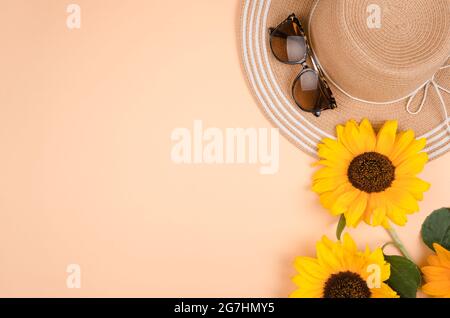 Flatlay con occhiali da sole, cappello di paglia e girasole giallo brillante su sfondo giallo. Foto Stock
